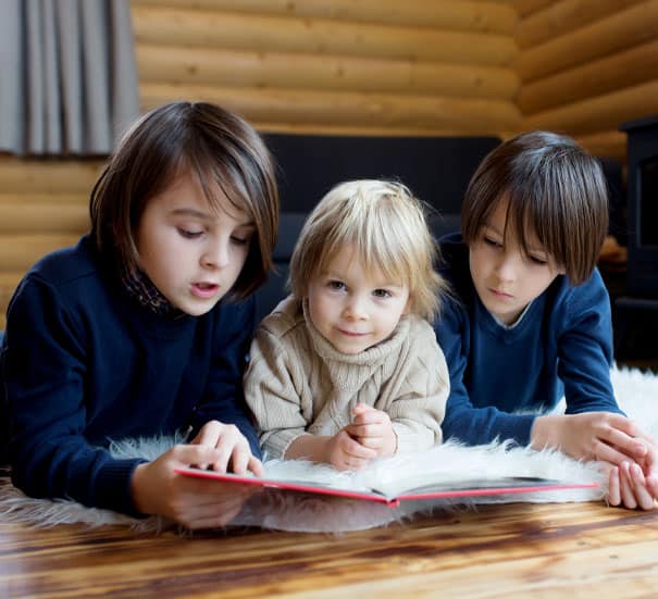 Kinder in einem Holzhaus, die ein Buch lesen